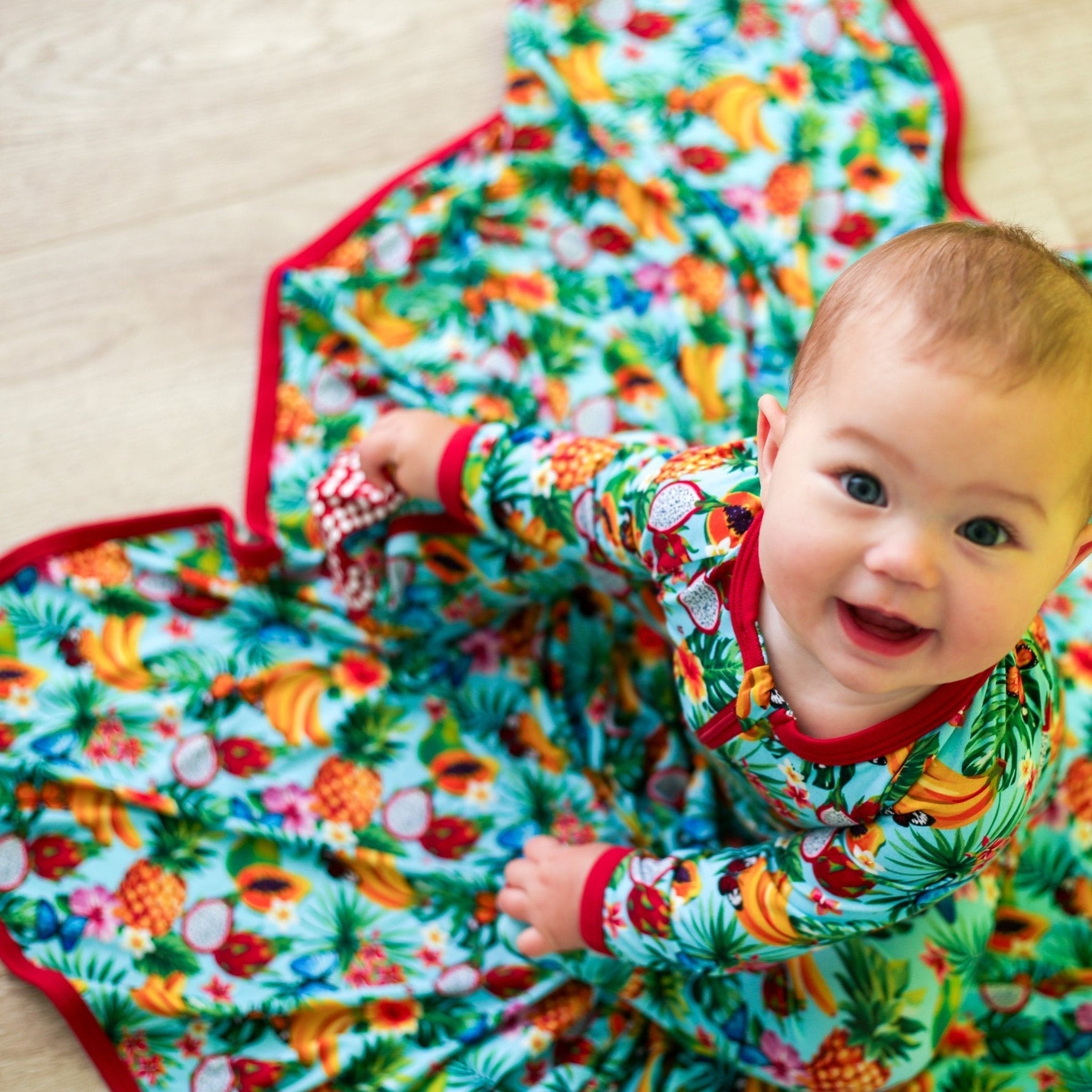 Swaddle blanket with a colorful tropical fruit print spread out flat