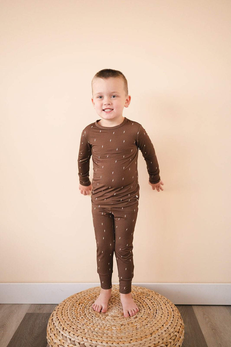 Two-piece pajama set for kids in brown with lightning design, featuring long sleeves and elastic waistband.