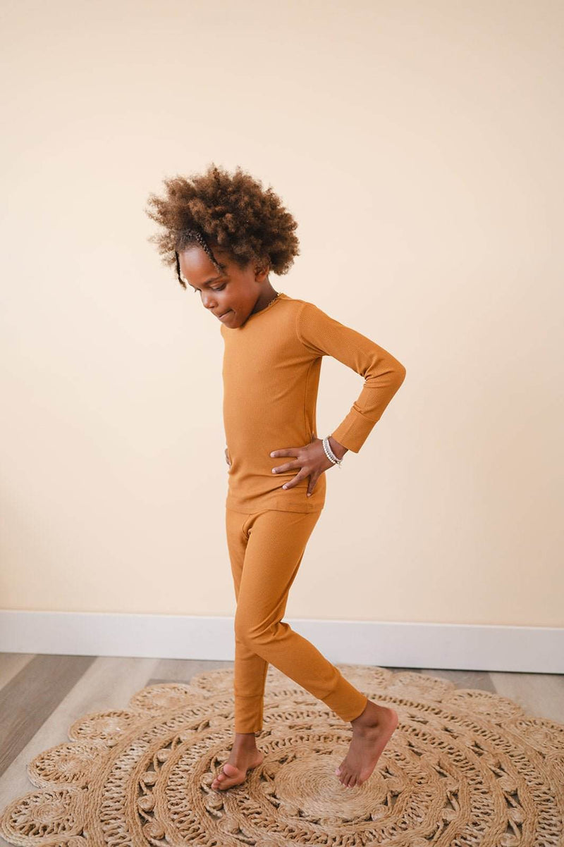 Child wearing Two-Piece Caramel Ribbed Pajama Set made from soft bamboo fabric with snug fit.