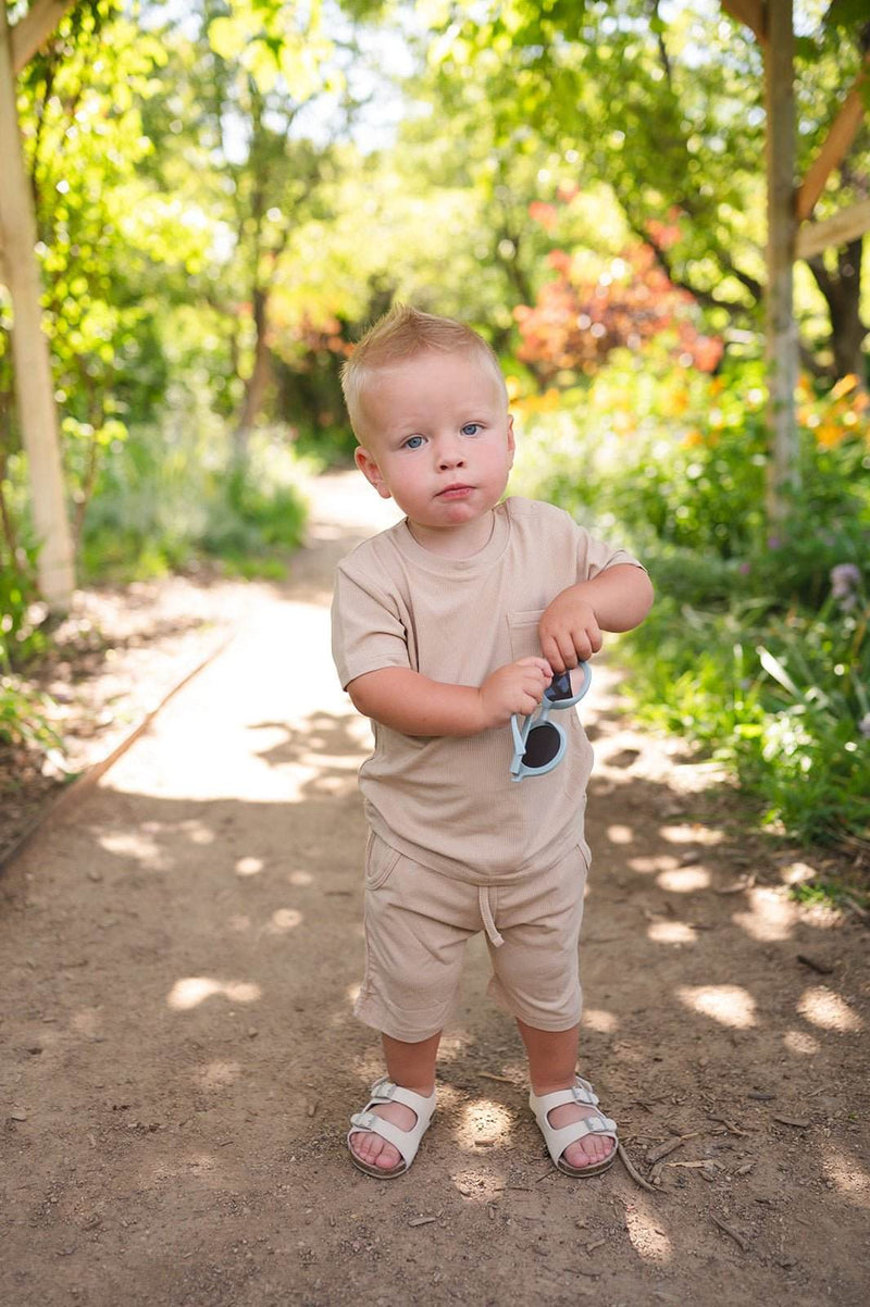 Tan two-piece ribbed short set for toddlers, featuring bamboo blend fabric with a pocket shirt and drawstring shorts.