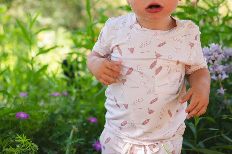 Cream two-piece short set with surfboard design, featuring a pocket shirt and drawstring shorts, made from soft bamboo fabric.