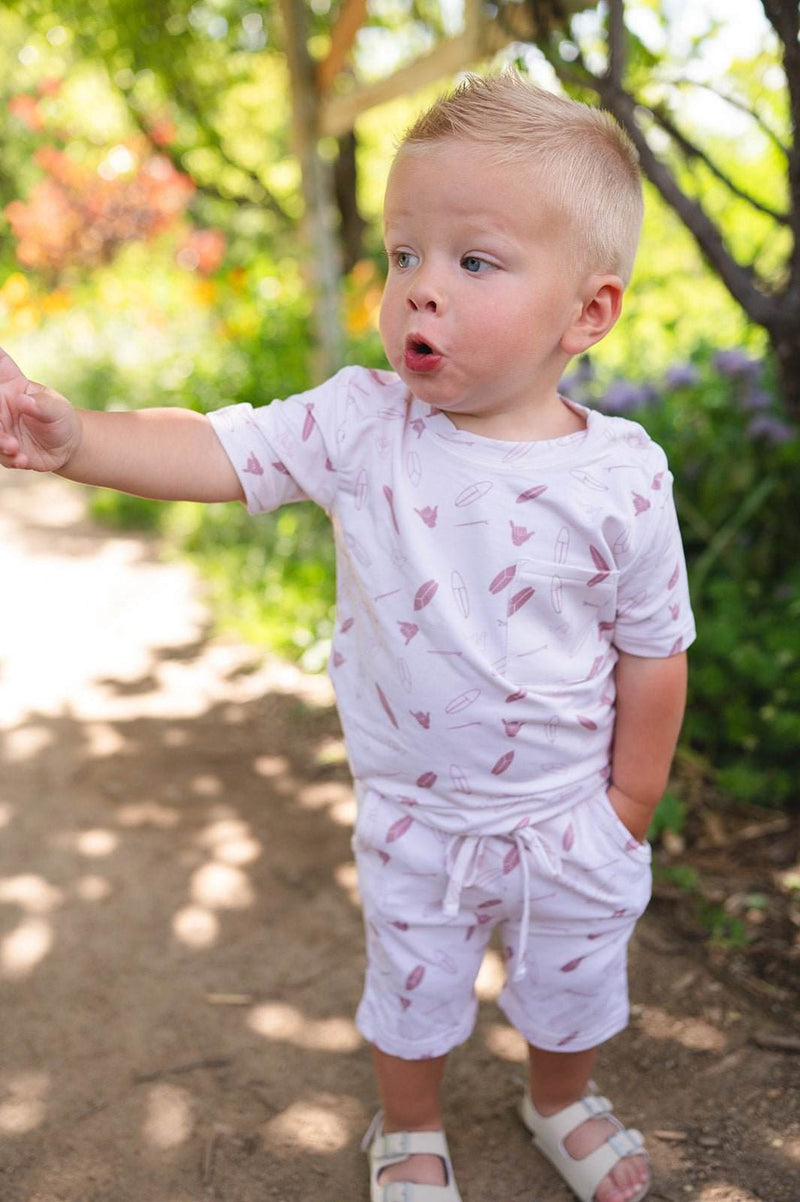 Toddler wearing a soft, lightweight two-piece short set with surfboard design and pockets, made from bamboo and spandex fabric.
