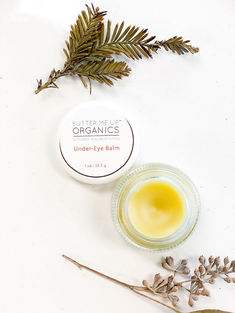 Caffeinated under eye balm in glass jar, shown with natural decor, targeting dark circles and puffiness.
