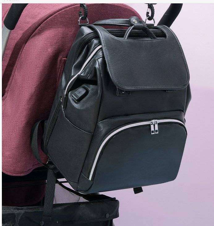 Unique backpack diaper bag in black PU leather, attached to a stroller.