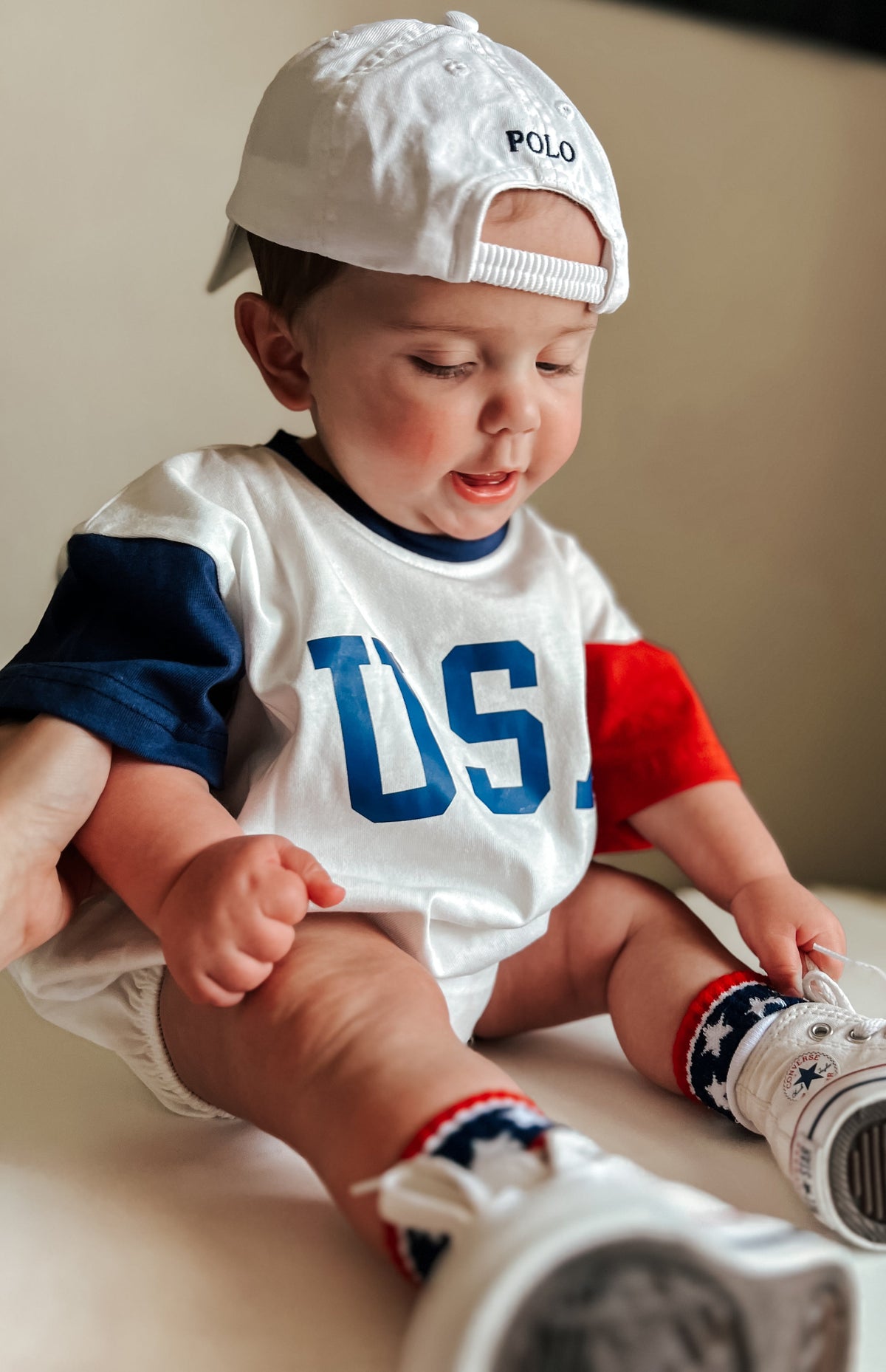 Baby wearing a red, white, and blue colorblock t-shirt romper from Little Joy Co., playing happily.