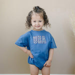 Little Joy Co. 100% cotton baby t-shirt romper in a neutral color, laid flat on a soft surface.