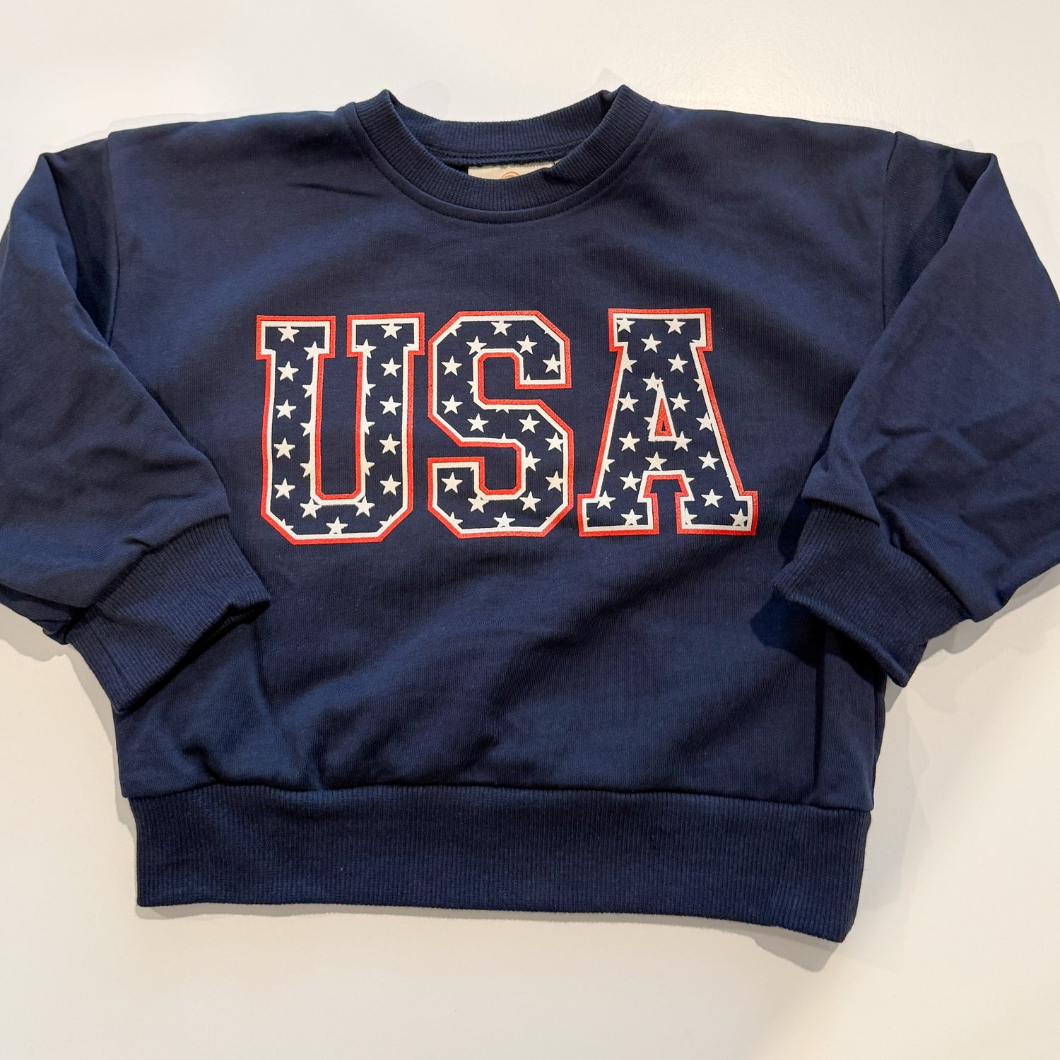 Little Joy Co. kids' crewneck sweatshirt with a red, white, and blue USA stars graphic.