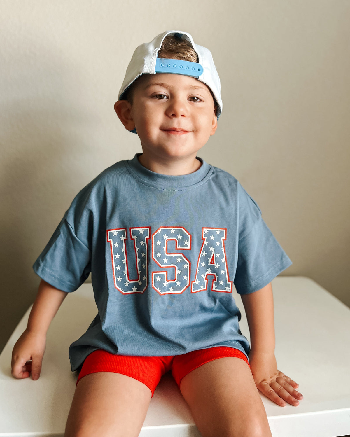 Child wearing a Little Joy Co. organic oversized tee in a natural setting, smiling and playing.