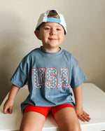Child wearing a Little Joy Co. organic oversized tee in a natural setting, smiling and playing.