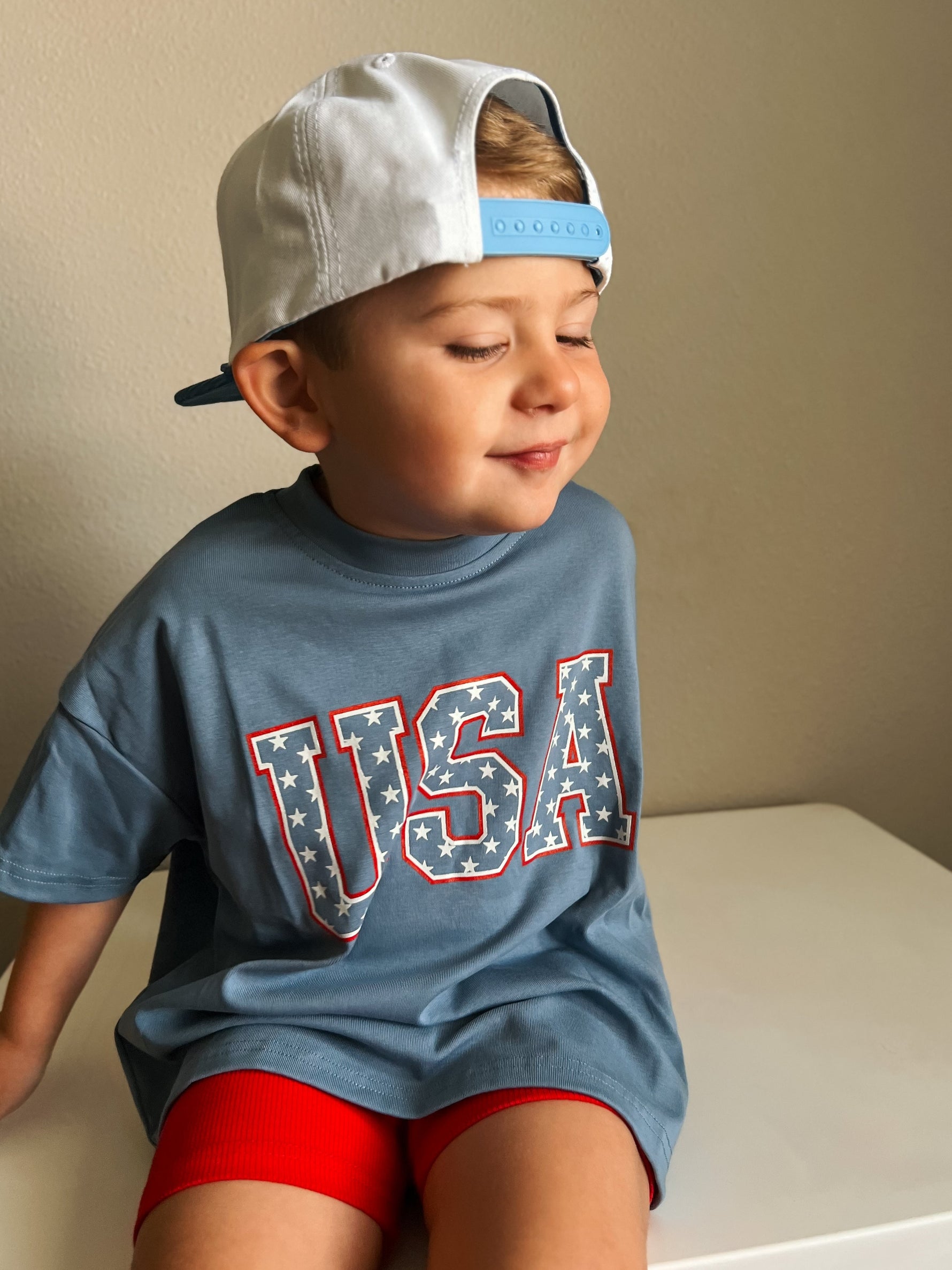 Child wearing a Little Joy Co. organic oversized tee in a natural setting, smiling and playing.