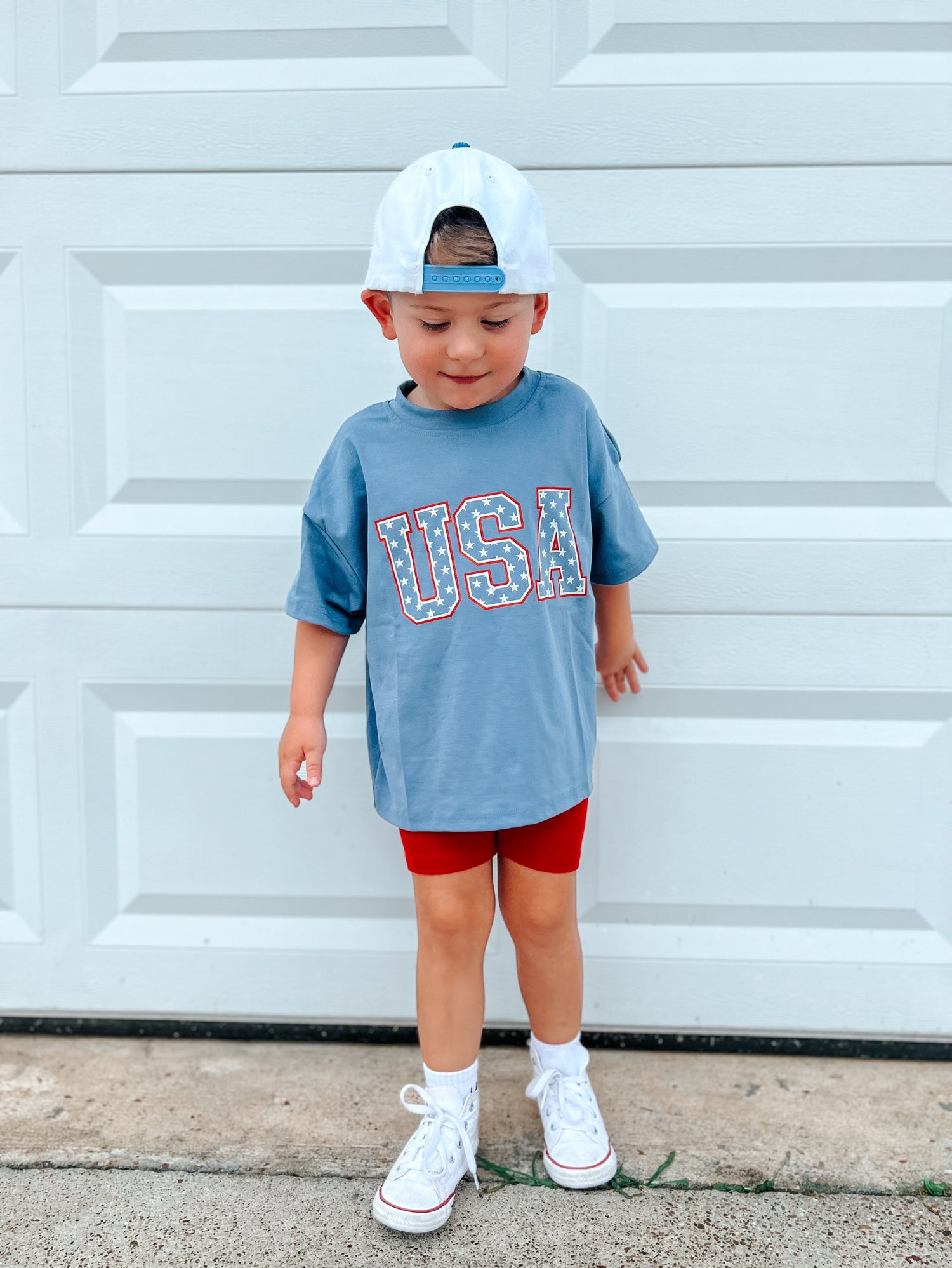 Child wearing a Little Joy Co. organic oversized tee in a natural setting, smiling and playing.