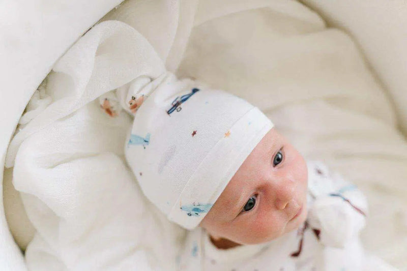 Newborn wearing a vintage airplane knot hat in soft, breathable fabric.