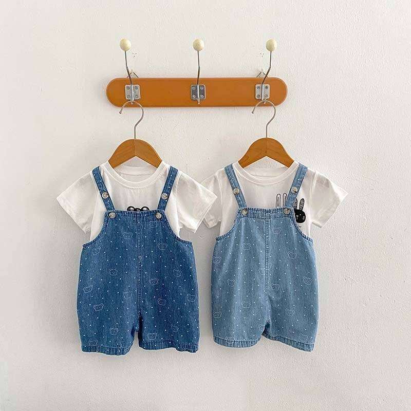 White Dots Denim Overalls hanging on wooden hooks.