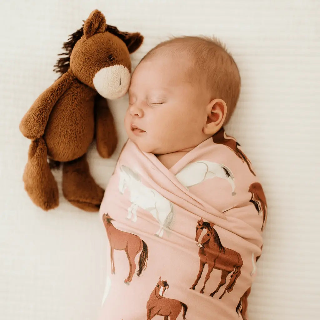 Baby swaddle blanket with a wild horses print laid out flat.