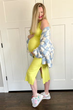 Model wearing a yellow ribbed maternity tank dress with a side slit, perfect for comfort and style.