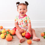 Baby bodysuit dress with a colorful citrus fruit print and long sleeves, with snaps at the inseam.