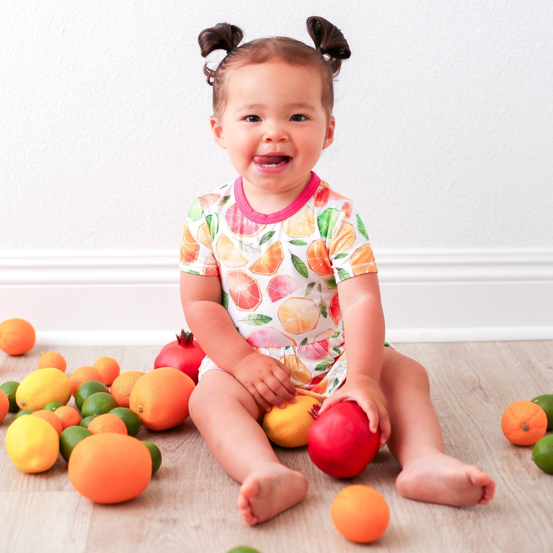 Baby bodysuit dress with a colorful citrus fruit print and long sleeves, with snaps at the inseam.