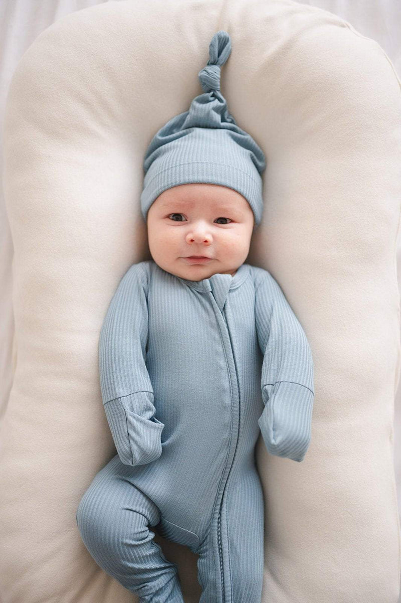 Zipper romper in arona blue ribbed bamboo viscose fabric with 2-way zipper, worn by a baby on a cushion.