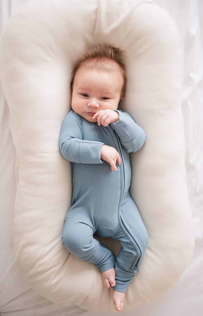 Zipper romper in arona blue ribbed bamboo viscose on baby lying down.