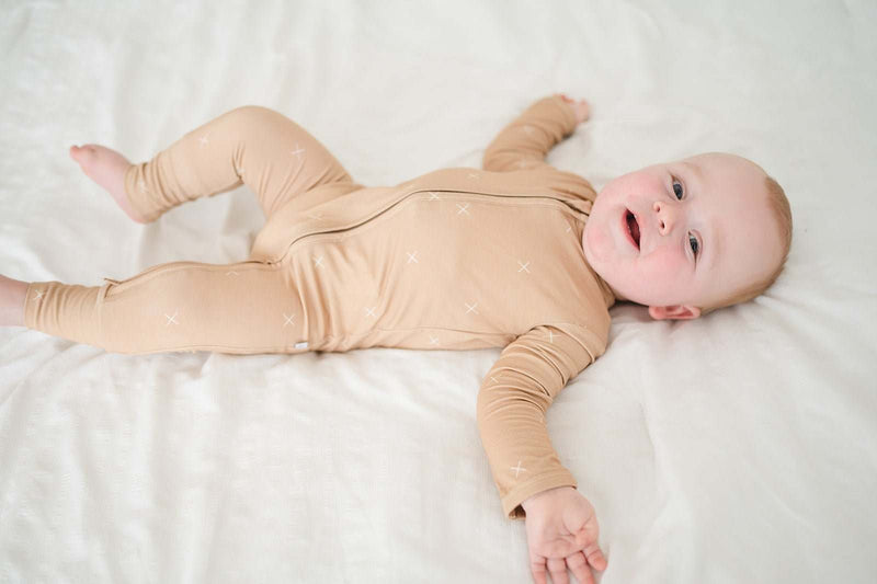 Baby wearing beige zipper romper with fold-over cuffs, made from soft bamboo viscose.