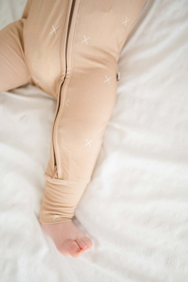 Beige baby romper with X's and a 2-way zipper for easy diaper changes.