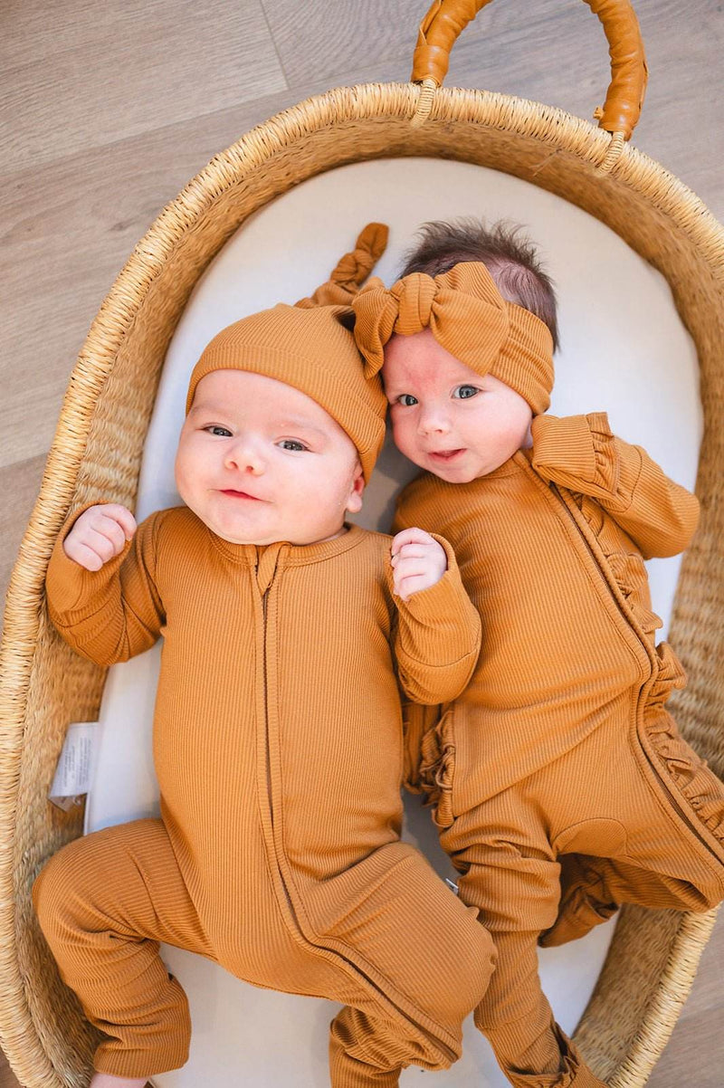 Caramel ribbed zipper romper with fold-over feet and hands on babies in a basket.