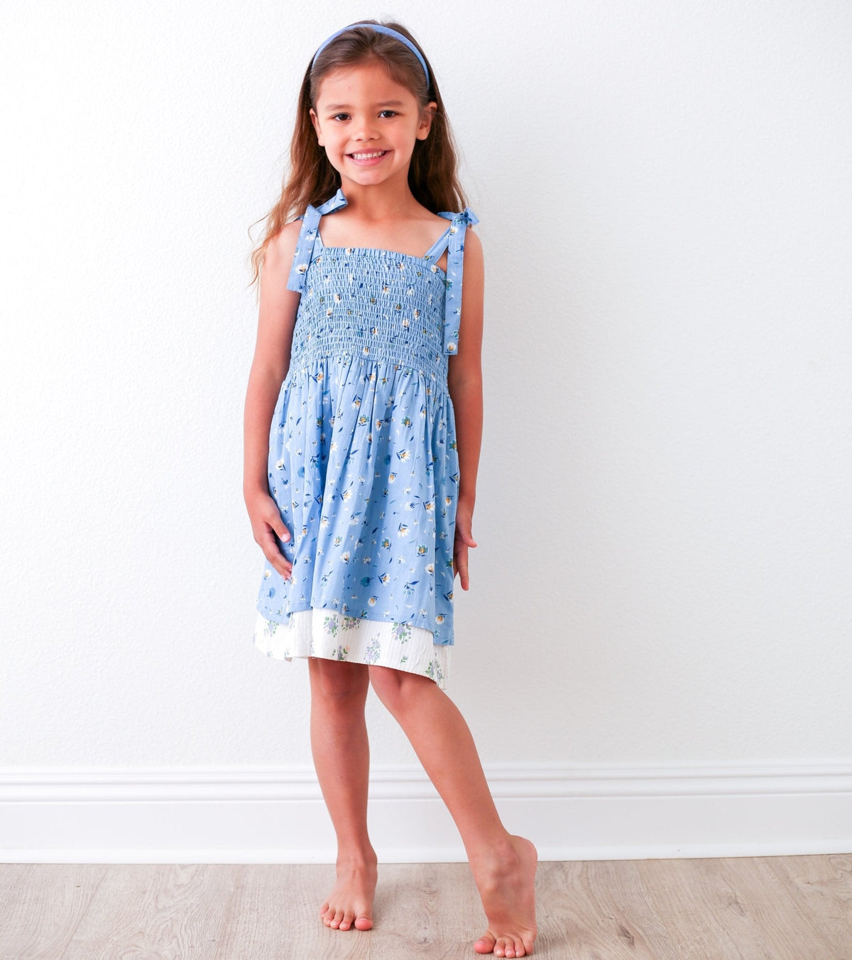 Blue floral baby dress with smocked top, tie straps, and a layered skirt