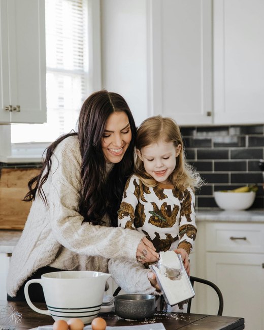 A mom and her young daughter baking together in the kitchen